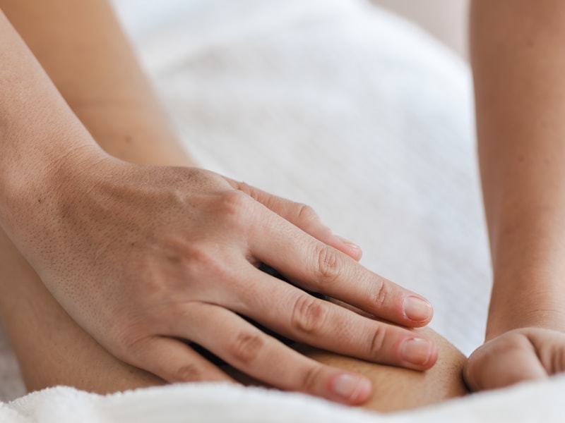 Massage technique applied along a client's calf and lower leg over a towel